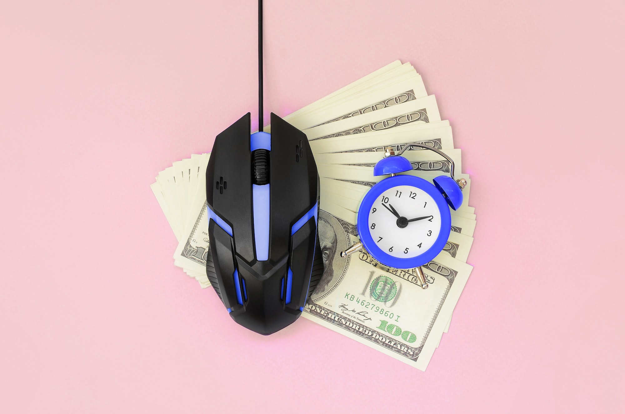 Computer mouse and small violet alarm clock on many dollar bills