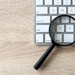 Magnifying glass on a white keyboard. Web search and SEO concept