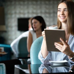 Young female entrepreneur reading electronic book on digital tablet in modern restaurant